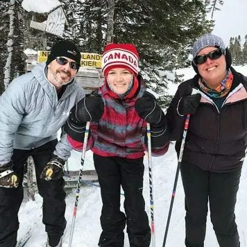 International student posing for a picture on cross-country skis with their host family