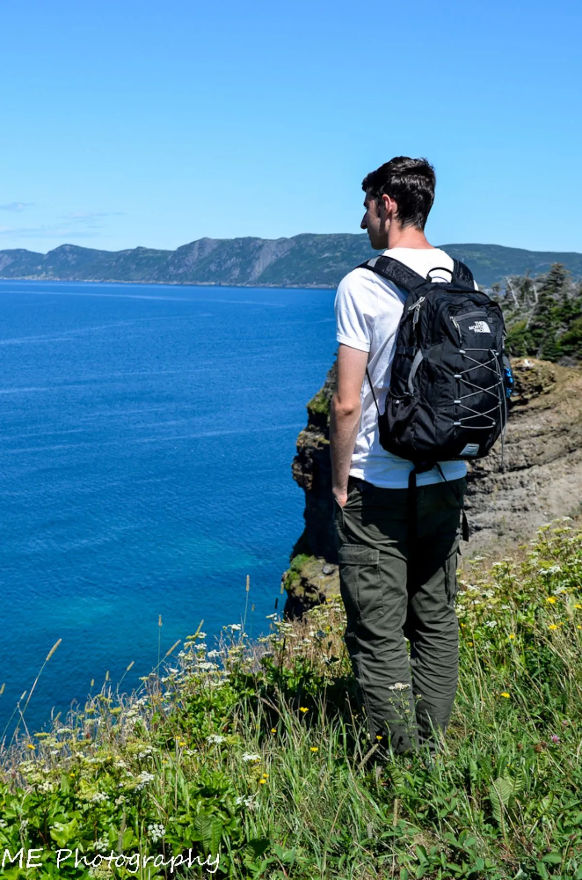 A student looking out over the ocean from a coastal cliff